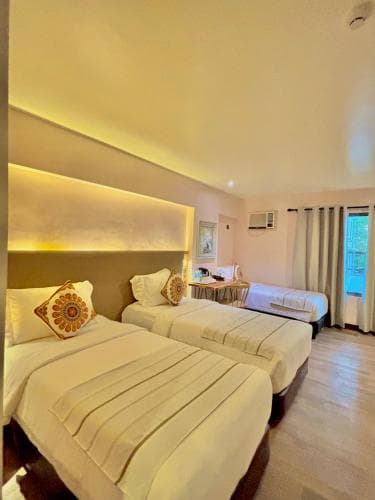 A cozy hotel room with two neatly made beds adorned with decorative pillows, soft lighting, and a serene atmosphere, ideal for travelers seeking comfort and relaxation.