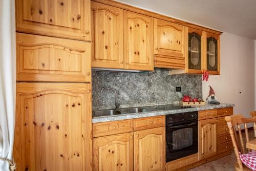 A cozy kitchen with rustic wooden cabinets, a granite backsplash, and a festive touch of red apples creates a warm, inviting atmosphere perfect for travelers seeking a homey retreat.