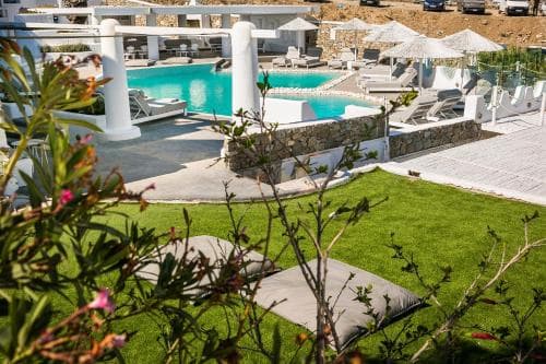 A serene resort scene featuring a vibrant turquoise pool surrounded by lounge chairs and umbrellas, framed by lush greenery and blooming flowers, ideal for a relaxing vacation getaway.