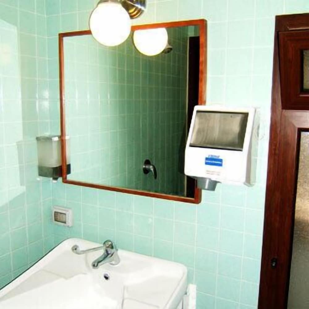 A cozy retro bathroom with mint green tiles, a white sink, wooden-framed mirror, and vintage lighting creates a nostalgic ambiance ideal for travelers seeking a charming accommodation experience.