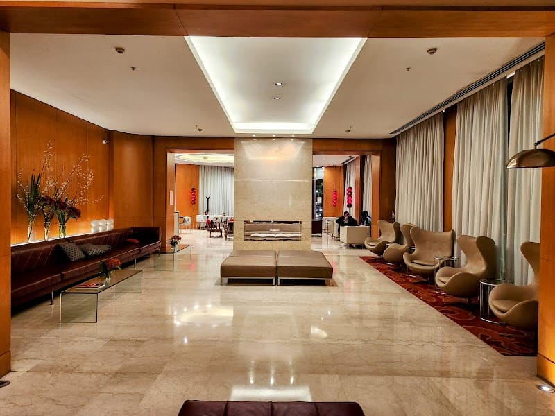 A spacious hotel lobby in Buenos Aires features elegant marble floors, modern seating arrangements, and warm lighting, creating an inviting atmosphere ideal for travelers seeking comfort and style during their stay.