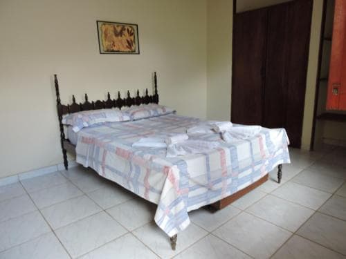 A cozy hotel room features a neatly made bed with a checkered quilt, tiled flooring, and simple decor, ideal for travelers seeking a comfortable and budget-friendly stay.