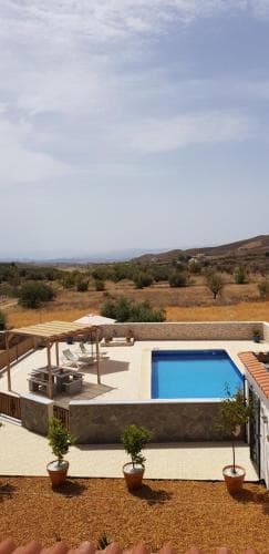 A serene private villa with a vibrant blue pool overlooks an expansive arid landscape under a clear sky, ideal for a tranquil getaway and perfect for travelers seeking relaxation in a secluded retreat.