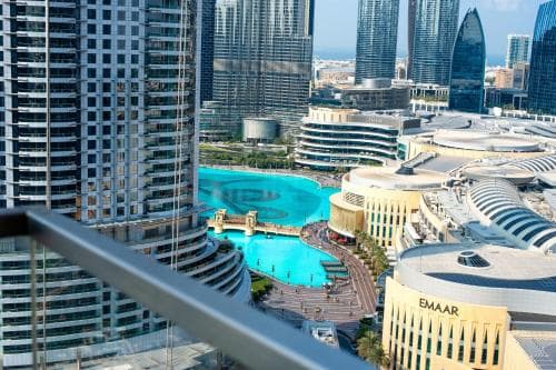 A vibrant cityscape featuring towering skyscrapers, a dazzling turquoise fountain, and modern architecture creates an exhilarating urban atmosphere ideal for luxury travel experiences.