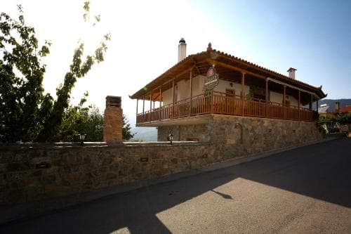 A serene countryside villa with a wooden balcony and stone walls bathed in golden sunlight, ideal for tranquil retreats and scenic stays.