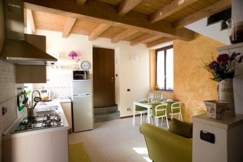 A cozy, rustic kitchen and dining area with wooden beams, warm yellow walls, and modern appliances creates an inviting atmosphere perfect for travelers seeking a charming countryside retreat.