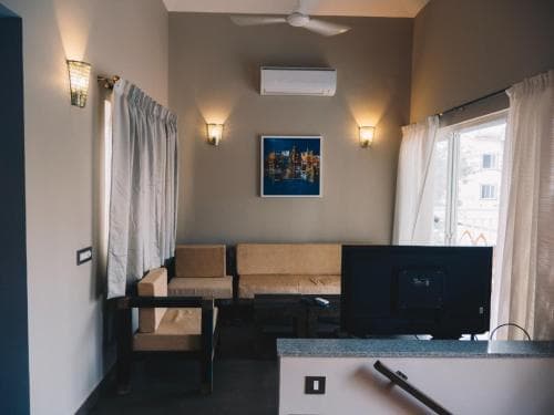 A cozy hotel room features modern furnishings, warm lighting, and a scenic view through large windows, ideal for travelers seeking comfort and relaxation.