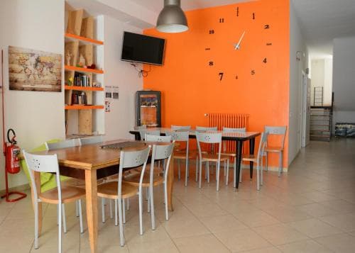A cozy café with vibrant orange walls, wooden tables, and chairs creates a welcoming atmosphere, perfect for travelers seeking a casual dining spot or a quiet workspace.