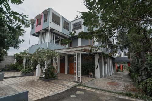 A serene, modern multi-story building surrounded by lush greenery offers a tranquil retreat, ideal for travelers seeking a peaceful accommodation experience.