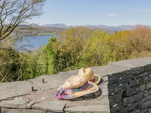 A serene lakeside vista from a stone wall adorned with colorful hats, perfect for a tranquil getaway in a lush, mountainous landscape ideal for nature lovers.