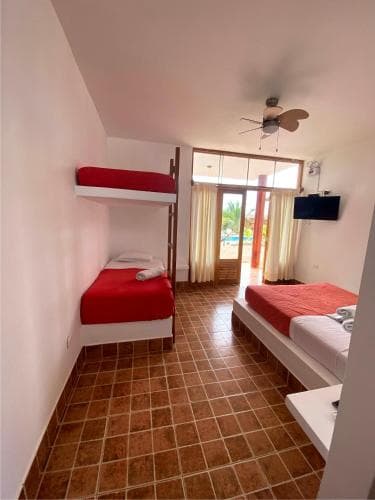 A cozy hotel room with red bunk beds, tiled floors, and a sliding glass door leading to a poolside view, ideal for budget-friendly family vacations.