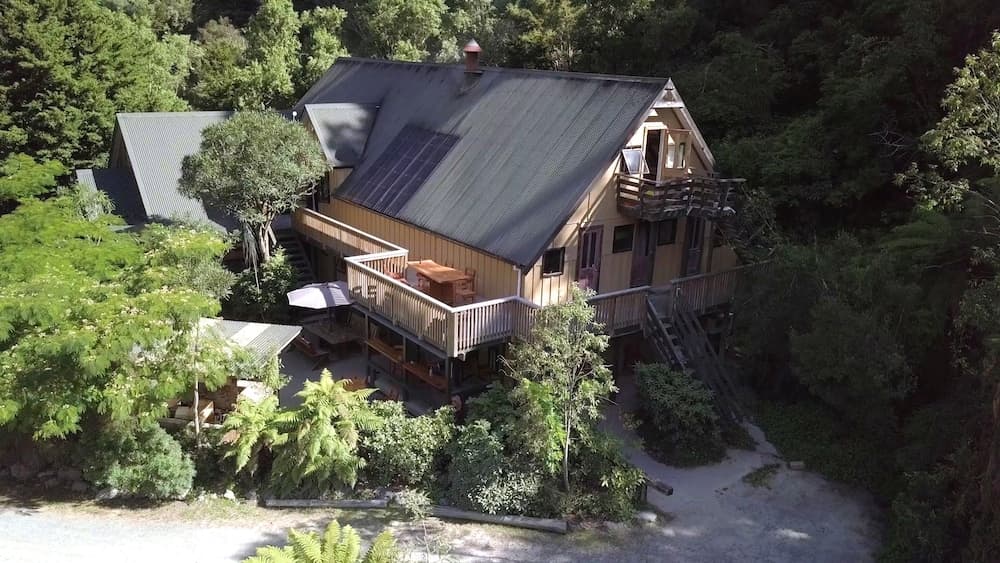 A serene forest retreat features a cozy cabin with wooden decks surrounded by lush greenery, ideal for nature lovers seeking a tranquil getaway.