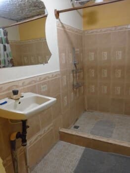 A cozy, vintage-style bathroom with beige tiled walls, a small sink, and a shower area, evokes a nostalgic mood ideal for travelers seeking quaint accommodations.