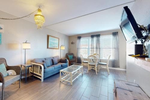 A cozy living room with modern furnishings, large windows letting in natural light, and a warm ambiance is ideal for travelers seeking comfort and relaxation during their stay.