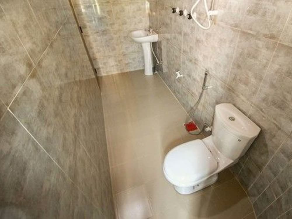 A clean, tiled bathroom featuring a toilet, sink, and shower area offers a functional space ideal for travelers seeking basic amenities in accommodations.