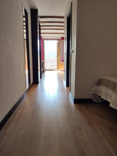 A cozy hallway with wooden floors leads to a bright balcony overlooking scenic views, ideal for travelers seeking a peaceful retreat in a charming accommodation.