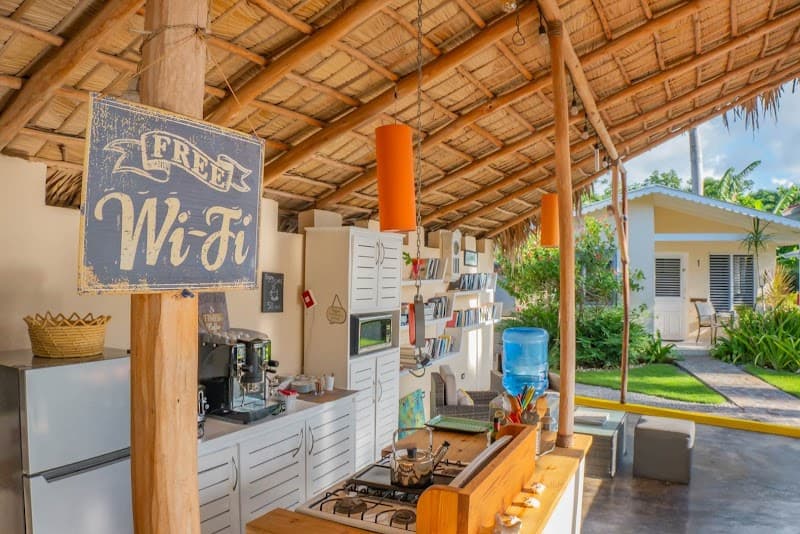 A cozy outdoor kitchen area under a thatched roof offers free Wi-Fi, modern appliances, and tropical greenery, perfect for travelers seeking relaxation and convenience at a beachside hotel in Las Terrenas, Dominican Republic.