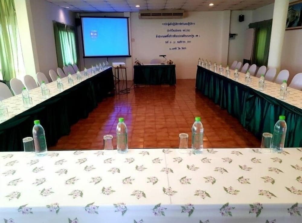 A professional conference room setup with green draped tables, water bottles, and a projector screen, ideal for business meetings or educational seminars.