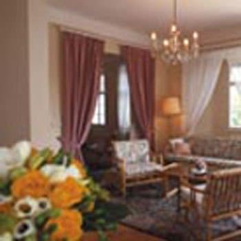 A cozy living room with plush seating, floral arrangements, and warm lighting creates an inviting atmosphere ideal for travelers seeking relaxation in a charming boutique hotel setting.