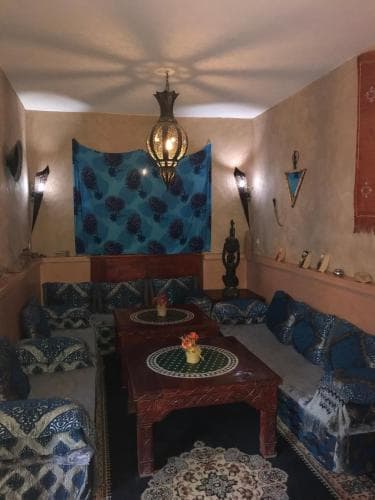 A cozy Moroccan-style lounge features plush blue patterned cushions, intricate rugs, and ornate lanterns, creating an inviting atmosphere ideal for cultural immersion and relaxation during travel.
