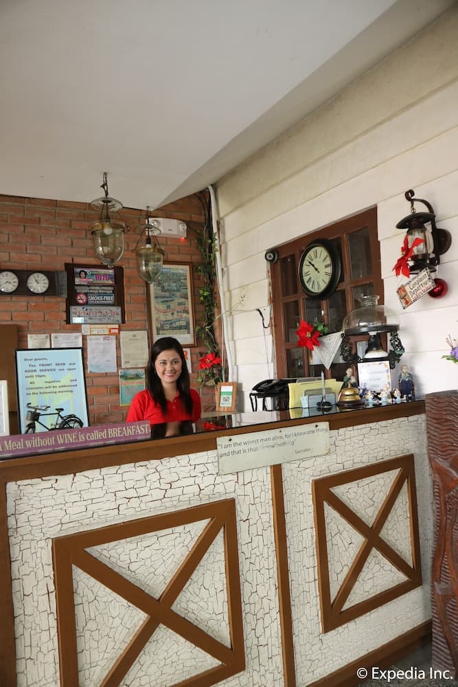A warmly lit reception area with rustic decor, including brick walls, vintage clocks, and decorative signs, creates an inviting atmosphere ideal for travelers seeking cozy accommodations.