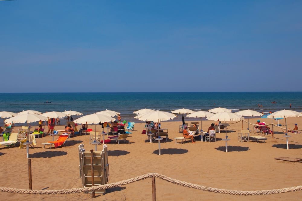 A serene beach scene with white umbrellas and lounge chairs under a clear blue sky, ideal for relaxing seaside getaways and capturing the essence of coastal leisure.