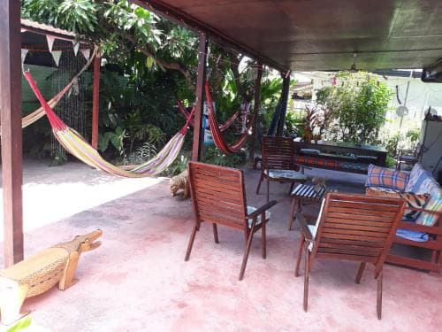 A cozy tropical patio features vibrant hammocks, wooden chairs, and lush greenery, creating a serene retreat ideal for relaxation during a vacation getaway.