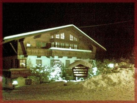 A cozy, illuminated chalet nestled in a snowy landscape at night offers a serene retreat for winter travelers seeking warmth and relaxation.