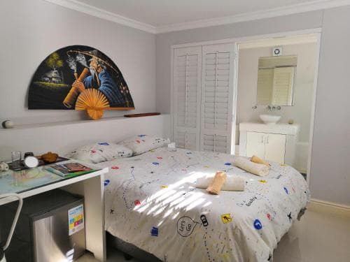 A cozy bedroom with a neatly made bed adorned with space-themed bedding, a vibrant wall art piece, and an attached bathroom, ideal for travelers seeking comfort and convenience in a compact living space.