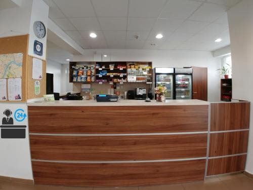 A cozy hotel lobby features a wooden reception desk, a well-stocked snack bar, and a welcoming atmosphere, ideal for travelers seeking convenience and comfort during their stay.