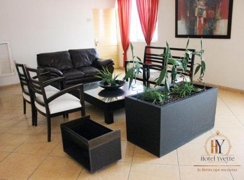 A cozy hotel lounge features modern furniture, vibrant red curtains, and indoor plants, creating a welcoming atmosphere ideal for travelers seeking relaxation.