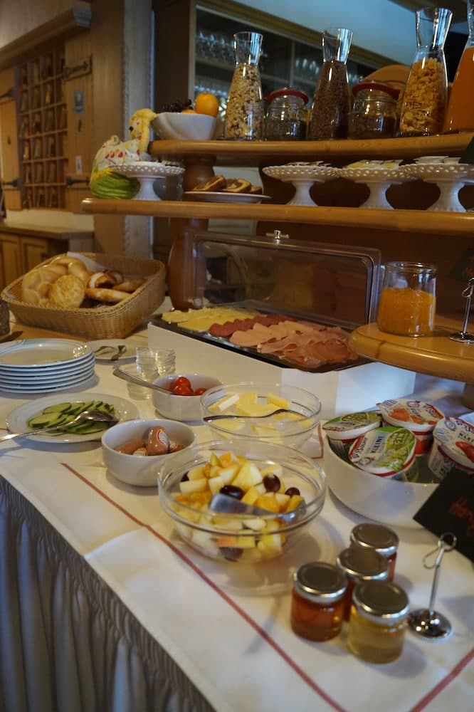A cozy breakfast buffet scene featuring fresh fruits, breads, meats, and jams on a well-organized table, ideal for travelers seeking a hearty morning meal in a warm, inviting setting.