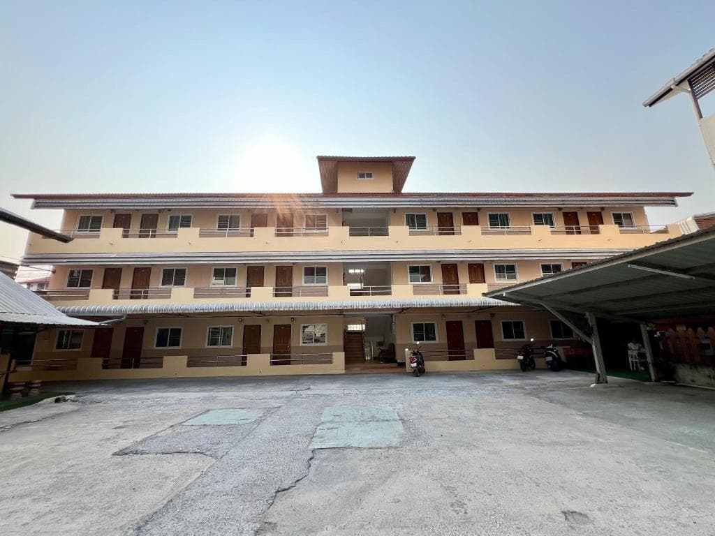 A serene courtyard of a multi-story guesthouse features parked scooters under a clear sky, ideal for budget travelers seeking accommodation in a quiet urban setting.