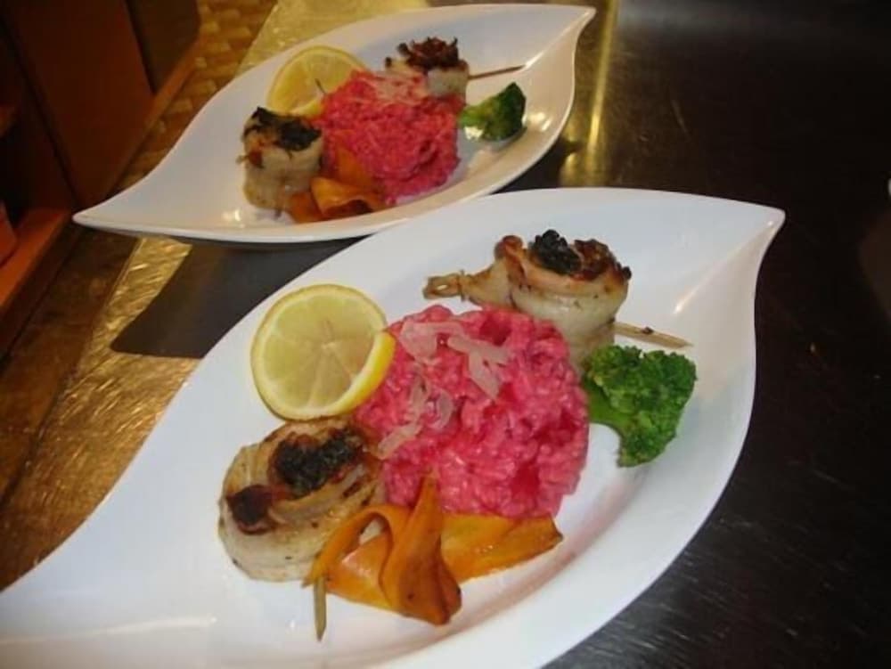 Elegant dining ambiance featuring vibrant pink risotto paired with grilled seafood skewers, garnished with lemon slices and vegetables, perfect for a gourmet culinary adventure.