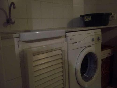 A cozy utility room featuring a washing machine, tiled walls, and a storage cabinet, ideal for travelers seeking practical accommodations with laundry facilities.
