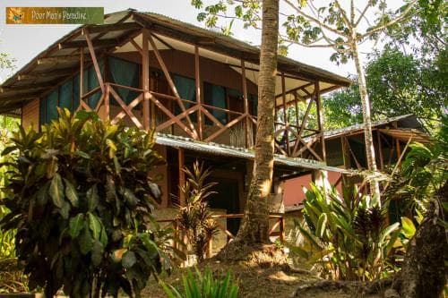 A serene tropical lodge surrounded by lush greenery offers a tranquil retreat for eco-tourists seeking adventure in nature.