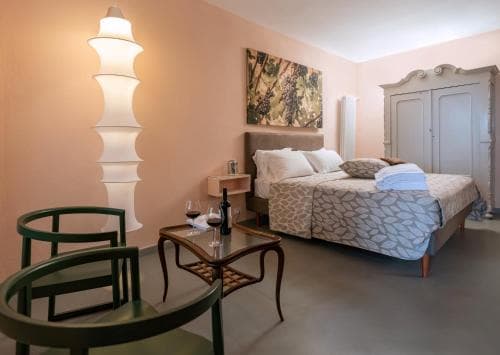A cozy hotel room with soft peach walls, vintage furniture, and a modern lamp creates an inviting atmosphere perfect for travelers seeking relaxation and comfort.