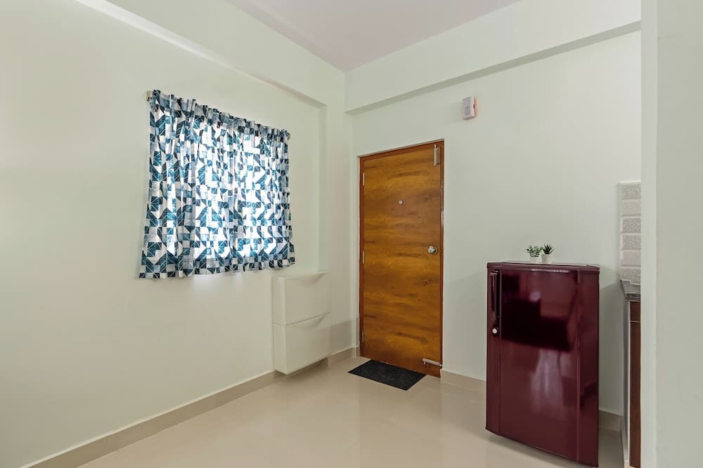 A cozy apartment entryway features a wooden door, patterned curtain, sleek refrigerator, and minimalist decor, ideal for travelers seeking a clean and modern living space.