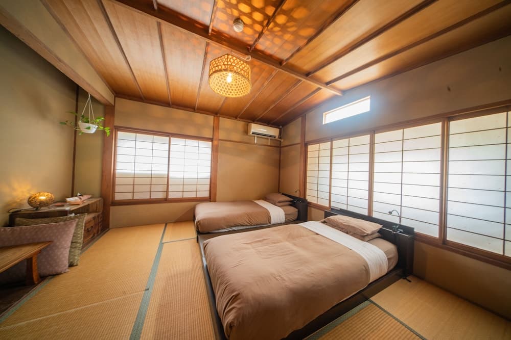 A serene Japanese-style guest room with tatami flooring, shoji screens, and traditional furnishings creates a peaceful atmosphere ideal for travelers seeking cultural immersion and relaxation.