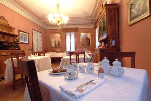 A cozy, warmly-lit dining room with elegant wooden furniture, white tablecloths, and vintage decor creates an inviting atmosphere perfect for a leisurely breakfast or intimate gathering during a heritage-themed getaway.