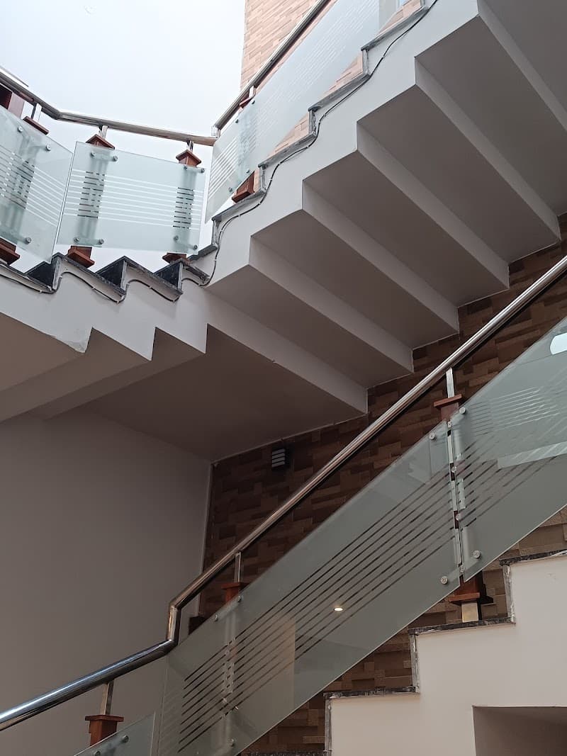 A modern staircase with glass railings ascends through a multi-level building in Kodaikanal, Tamil Nadu, offering a sleek and contemporary design ideal for travelers seeking upscale accommodations.