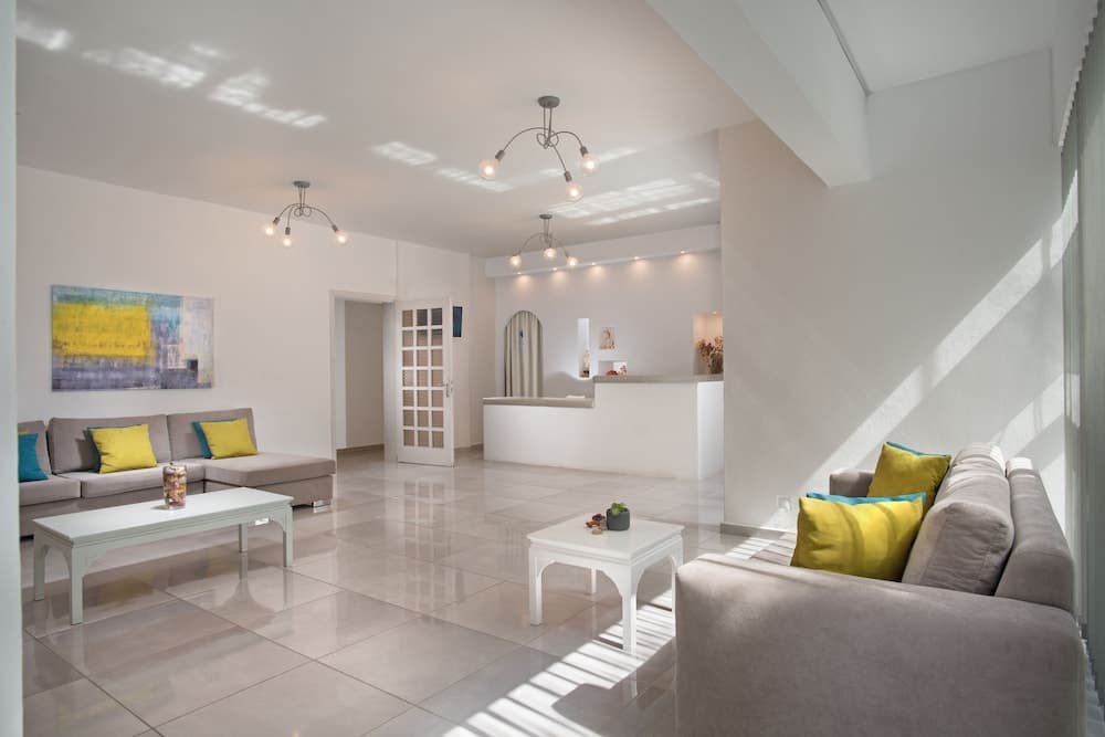 A bright, modern living room with sleek white furniture, vibrant yellow cushions, and natural light streaming through large windows creates an inviting atmosphere ideal for a relaxing vacation rental.