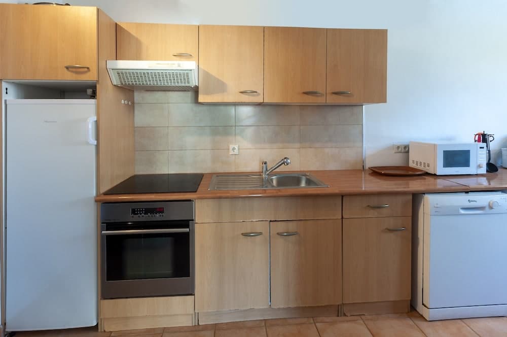 A cozy, well-equipped kitchen featuring wooden cabinets, a stainless steel sink, modern appliances like a refrigerator, oven, microwave, and dishwasher, ideal for travelers seeking self-catering accommodations.