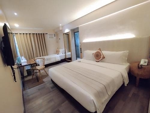 A cozy hotel room features a neatly made bed, modern furnishings, and soft lighting, creating a welcoming atmosphere ideal for travelers seeking comfort and relaxation.