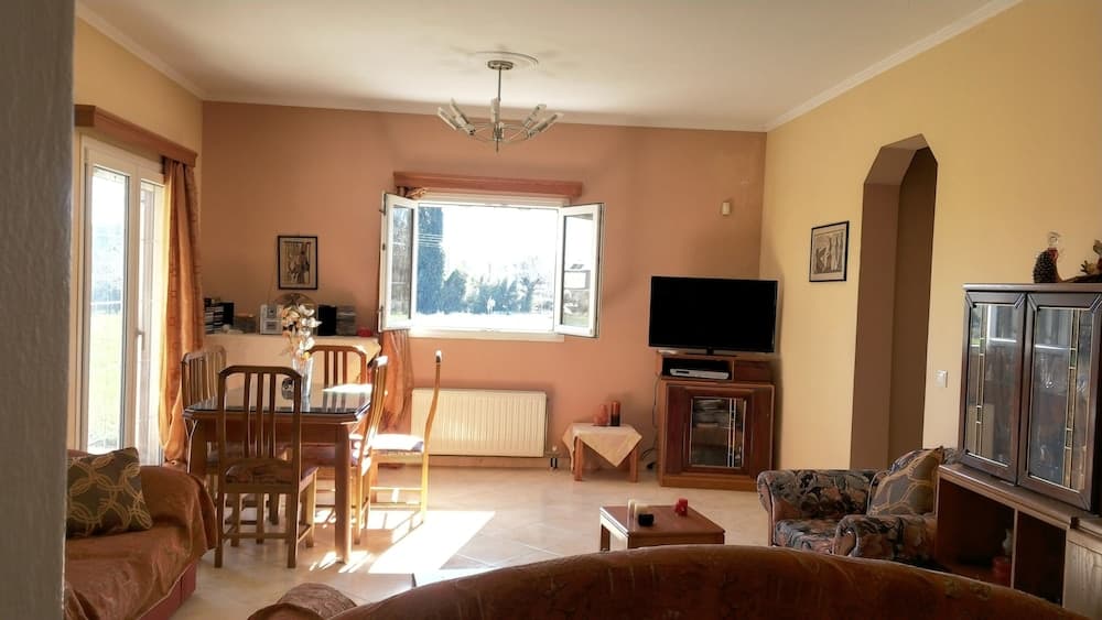 A cozy living room with warm-toned walls, wooden furniture, and large windows inviting natural light, ideal for travelers seeking a comfortable and homely accommodation experience.