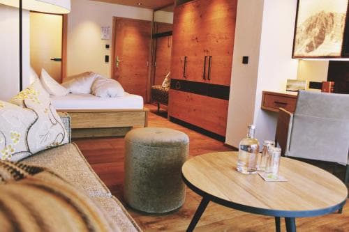 A cozy hotel room with wooden accents, plush seating, and a neatly arranged table with refreshments invites travelers seeking comfort and relaxation.