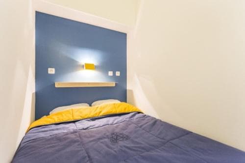 A cozy bedroom with a blue accent wall, yellow bedding, and a minimalist shelf creates a serene atmosphere, ideal for travelers seeking a tranquil and stylish accommodation.