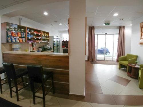 A cozy hotel lobby features a well-stocked snack bar, comfortable seating areas, and a bright view of parked cars outside, ideal for travelers seeking convenience and relaxation during their stay.