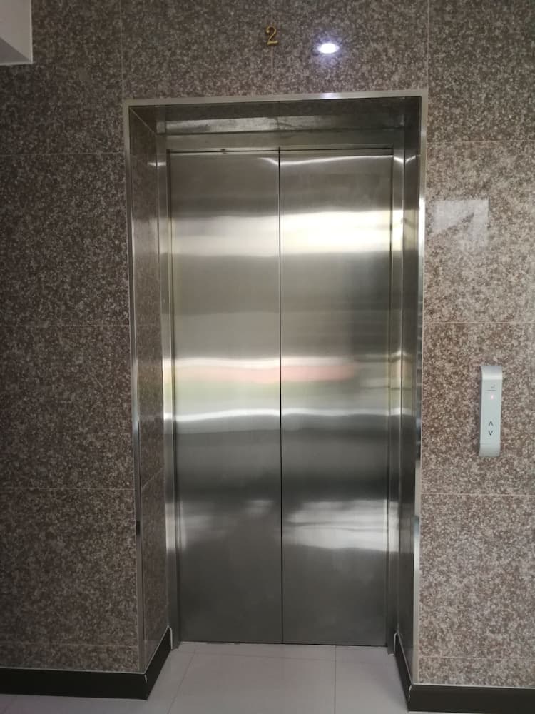 A sleek stainless steel elevator set within a granite-walled lobby exudes modern sophistication, ideal for travelers seeking efficient vertical transport in upscale urban accommodations.