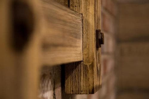 A rustic wooden cabinet with a metal latch stands against a brick wall, evoking a cozy, vintage atmosphere ideal for travelers seeking charming, historic accommodations.